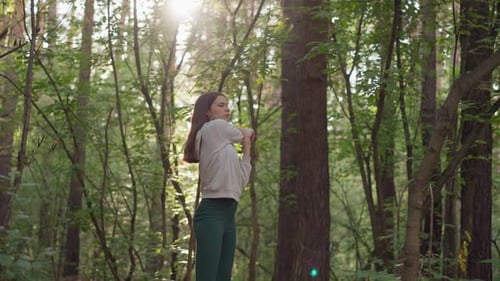 Woman Athlete Stretches Arms in Forest