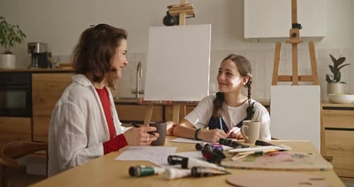 Happy Brunette Woman Patting Her Daughter on the Shoulder During a Drawing Lesson in the Art Room at