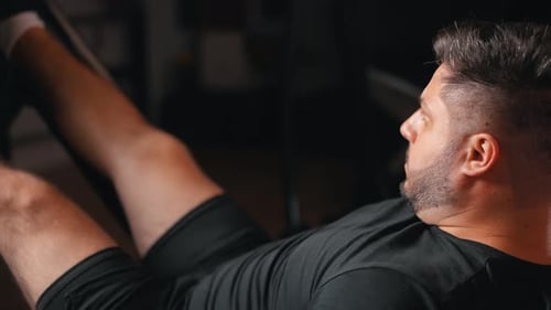 Young man intense leg press machine bodybuilding workout training in in dark fitness gym