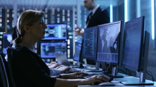 Der Vorgesetzte hält ein Briefing für seine Mitarbeiter im System Control Center voller Monitore und Server ab.