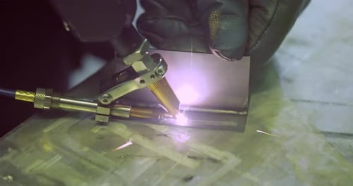 Laser welding machine with hand hold gun. Laser welding is shown in close-up.