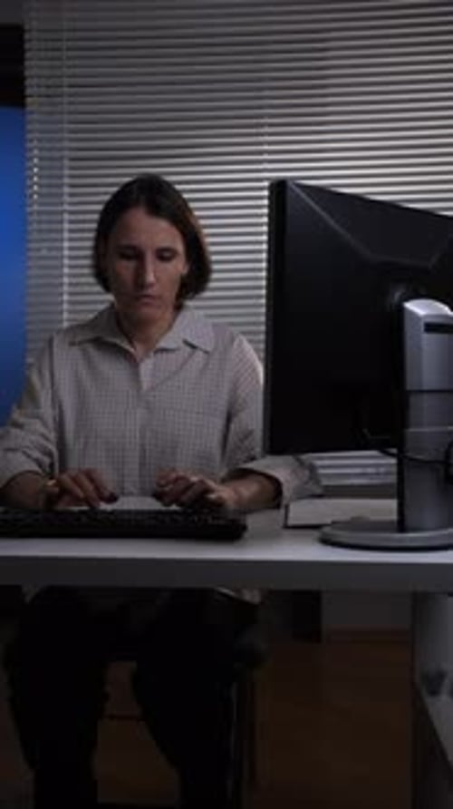 Vertical Video Woman Focusing Intently on Her Computer Screen Typing on a Keyboard at Her Desk in a