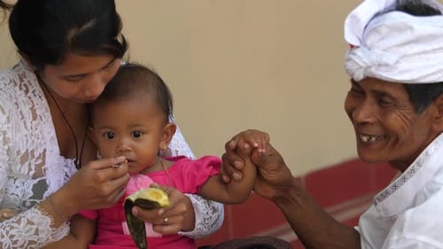 Mother Feeds Baby as Man Looks On