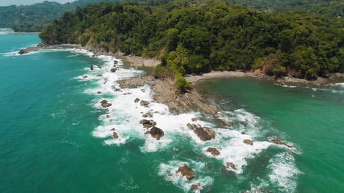 Rocky coastline with turquoise ocean waves on a clear sunny day in Costa Rica