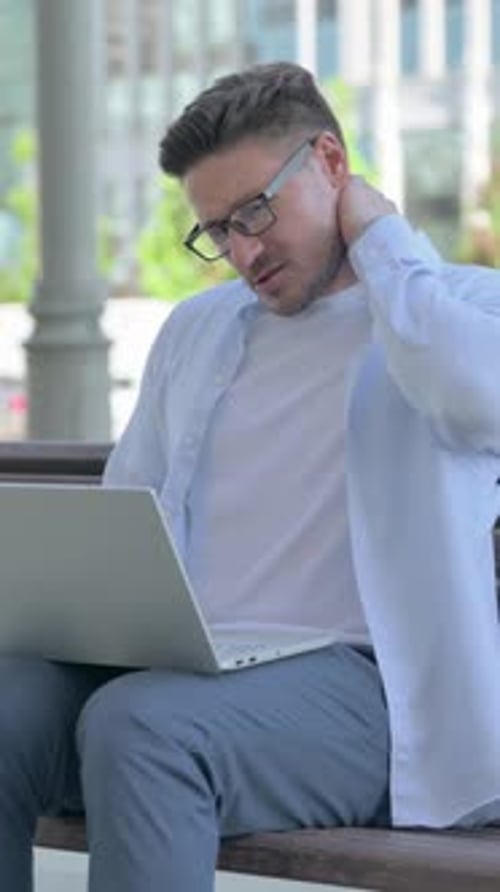 Man Sitting on Bench Working on Laptop Outdoors