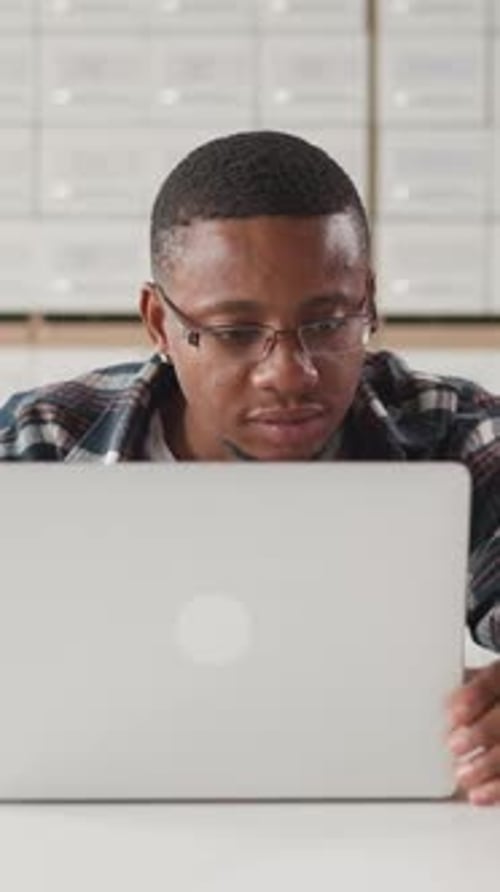 Black Man Works on Laptop in Library