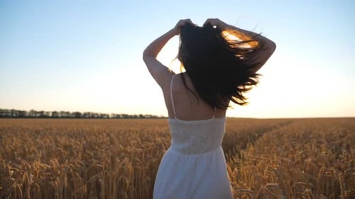 Carefree Woman Playing with Her Hair and Running Across Wheat Field Happy Girl in White Dress
