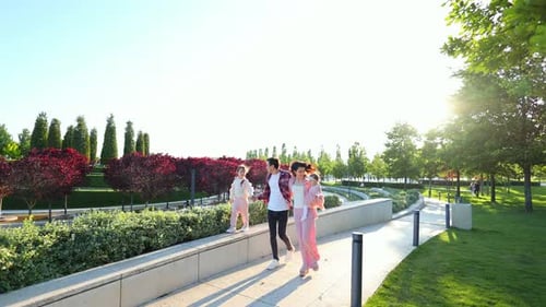 Young Happy Family Strolls Through a Beautiful Modern Park at Sunset