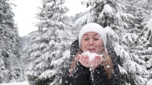 Young Beautiful Woman Playing with Snow in the Winter Forest