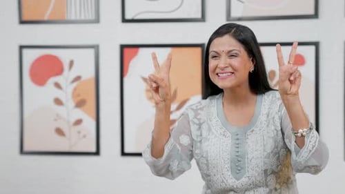 Smiling Woman Points and Makes Peace Sign