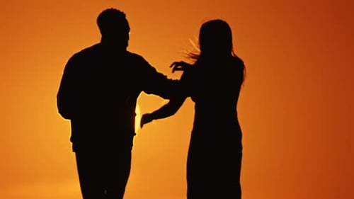 Silhouetted Couple Dancing at Orange Sunset