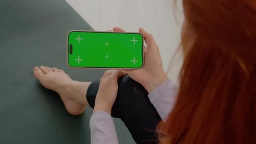 Woman using green screen smartphone during gym break at home