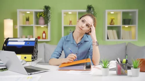 Woman Reads Through Binder at Bright Desk
