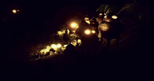 La lumière chaude de la poterie aux chandelles est exposée dans un cadre extérieur serein la nuit