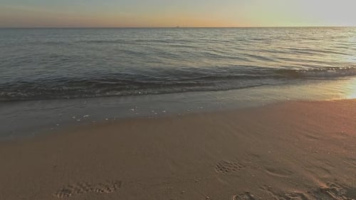 Very early morning at the calm sea shore beach with tiny waves and clear water and sky