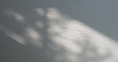 Abstract Sunlight Patterns on a Grey Textured Wall
