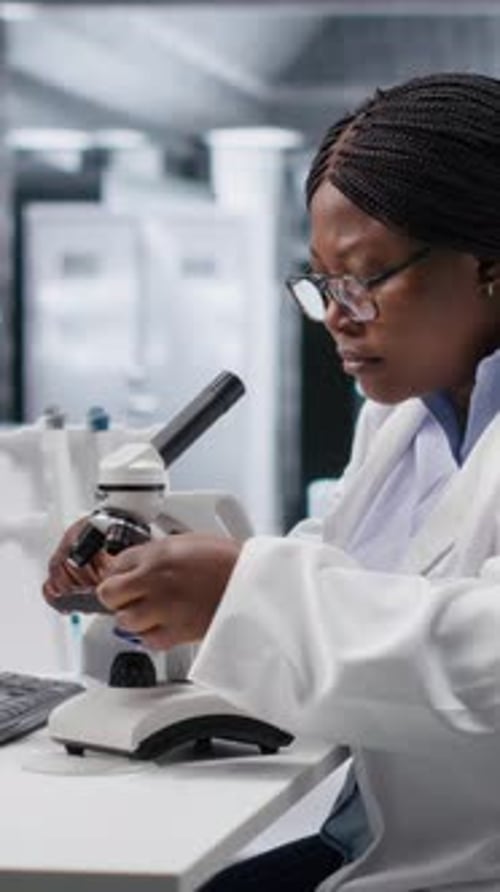 Vídeo vertical: Pesquisadora negra estuda amostras de biologia molecular em um laboratório