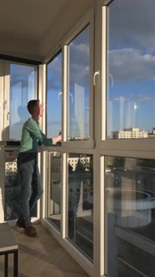 Man Stands On Balcony Of High Rise Building