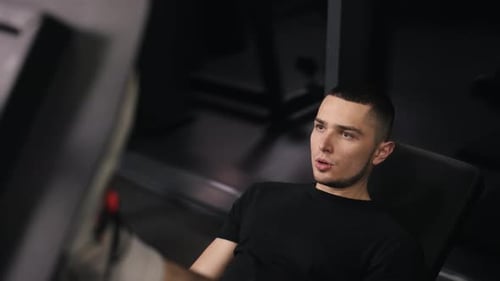 Man Leg Pressing in Dark Gym