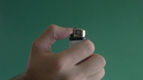 Hand ignites lighter with flame on green screen