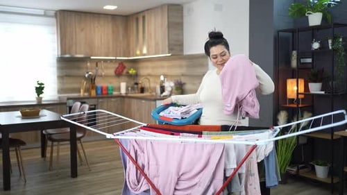 Woman Hanges Laundry on Clothes Rack Indoors