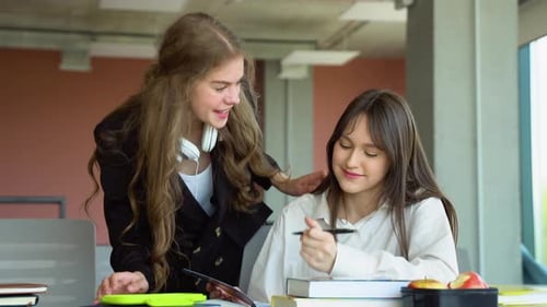 Two Students Doing Homework Together and Helping Each Other Sitting in a Table at University