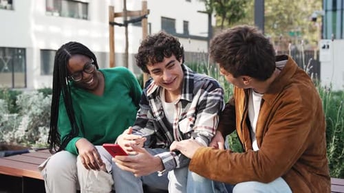 Three Young Adults Laughing at a Smartphone