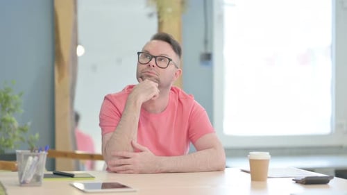 Thoughtful Man Sitting at Desk in Office
