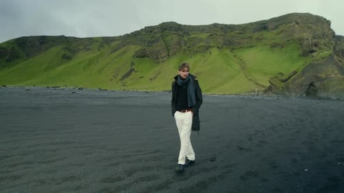 A Young Man is Walking Along the Stunning Reynisfjara Black Sand Beach Located in Iceland
