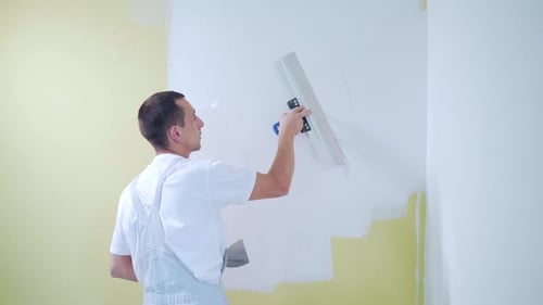 Man Applies Plaster to Wall in Bright Interior