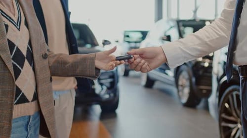 Anonymous Car Salesman Giving Buyers Key to New Car and Shaking Hands