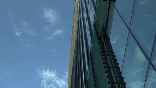 Upward view of modern skyscraper with detailed facade against blue sky