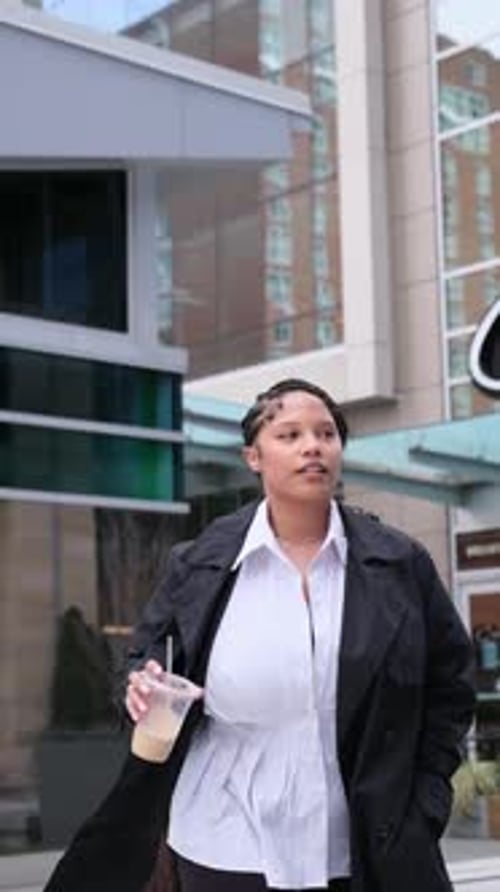Stylish Woman Walking Through City with Drink