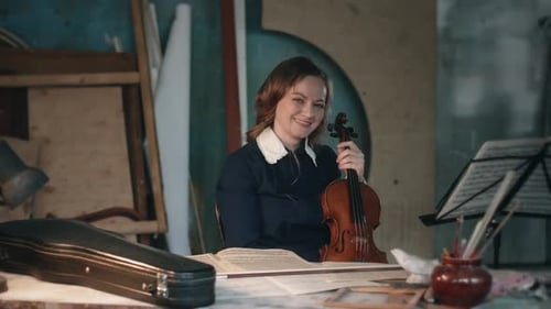 Woman Holds Violin and Smiles at Music Studio
