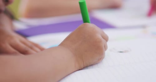 Child Drawing with a Green Marker at School