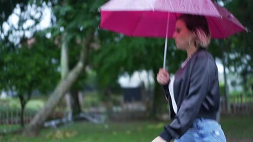 Young woman holding umbrella walking outside during rain