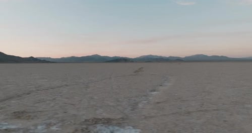 a large flat desert with mountains in the background