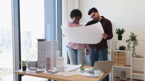 Dedicated Architects Examining Blueprint for Modern Urban Project