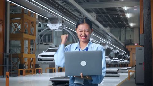 Une professionnelle asiatique se fixe un objectif lorsqu'elle utilise un ordinateur portable dans une usine de voitures électriques