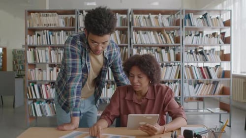 Étudiants multiraciaux faisant leurs devoirs à la maison ensemble dans la bibliothèque