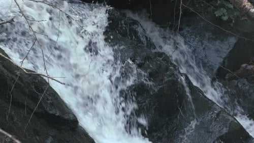 Flooding clear water down the stream in nature. Slow dolly track shot of small waterfall,close up.