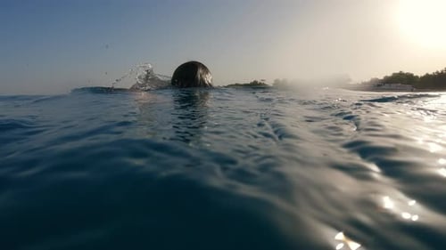 Niño nadando en estilo libre en el mar durante el amanecer