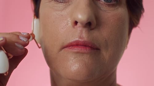 Kaukasische Frau massiert Gesicht mit Jade Roller