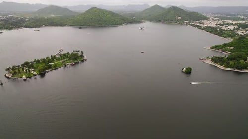 Aerial dolly in revealing speedboat sailing big lake in Udaipur, India.