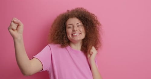 Woman with Curly Hair Celebrates Against Pink Background