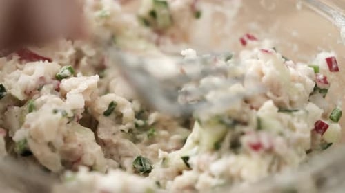 Close up of mixing vegetable spread with fork; smashed white bean with radish, chives and cucumber,