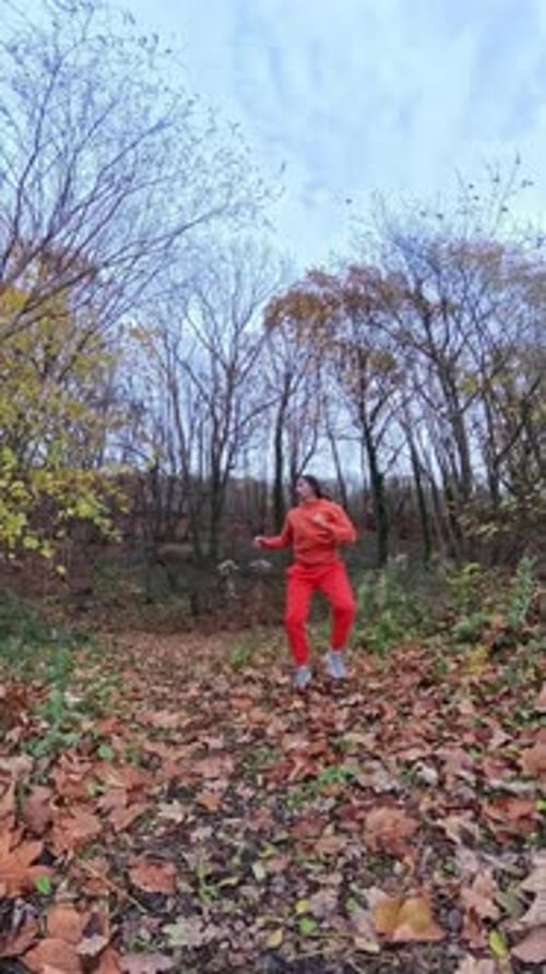 Woman in Orange Jumpsuit Performs Splits in Forest