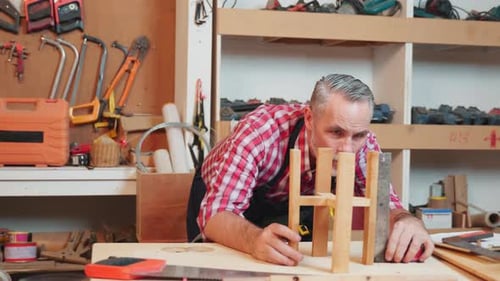 Senior Carpenter Uses a Ruler and Set Square to Measure and Assemble a Wooden Structure with Precise