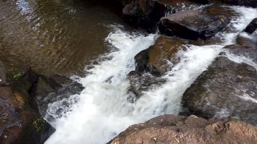 Stream of water flowing between the rocks with foam falling through a waterfall in a pleasant enviro