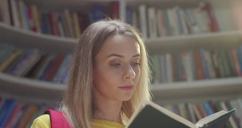 Portrait of Young Caucasian Pretty Blonde Female Student Reading Book and Smiling to Camera in